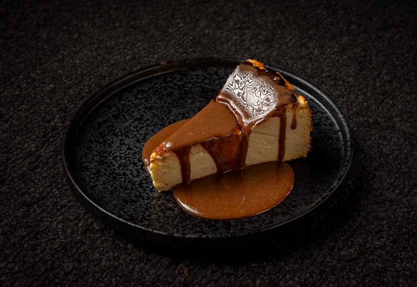 A slice of burnt Basque cheesecake with toffee sauce poured over