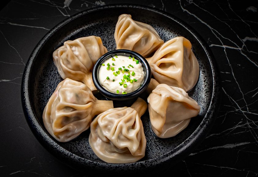 Georgian khinkali dumplings arranged around a bowl of sour cream