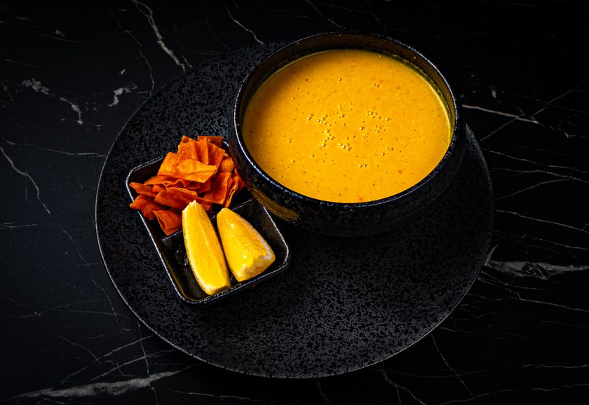 Smooth golden lentil soup with lemon wedges