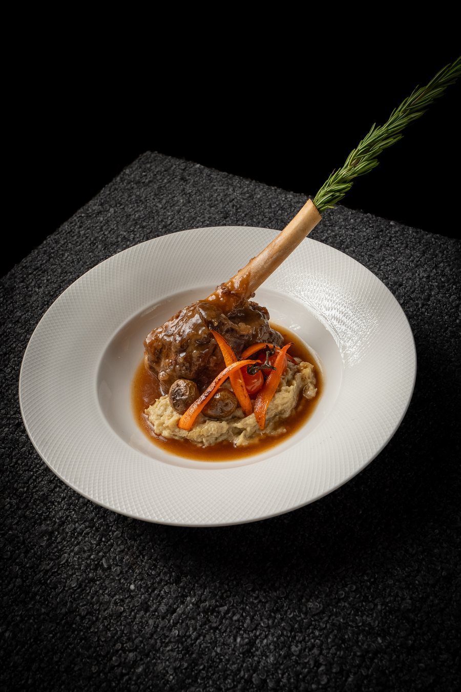 Slow-braised lamb shank on the bone with roasted vegetables and jus