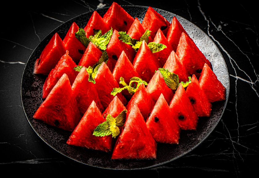 Chilled watermelon slices arranged on a dark plate