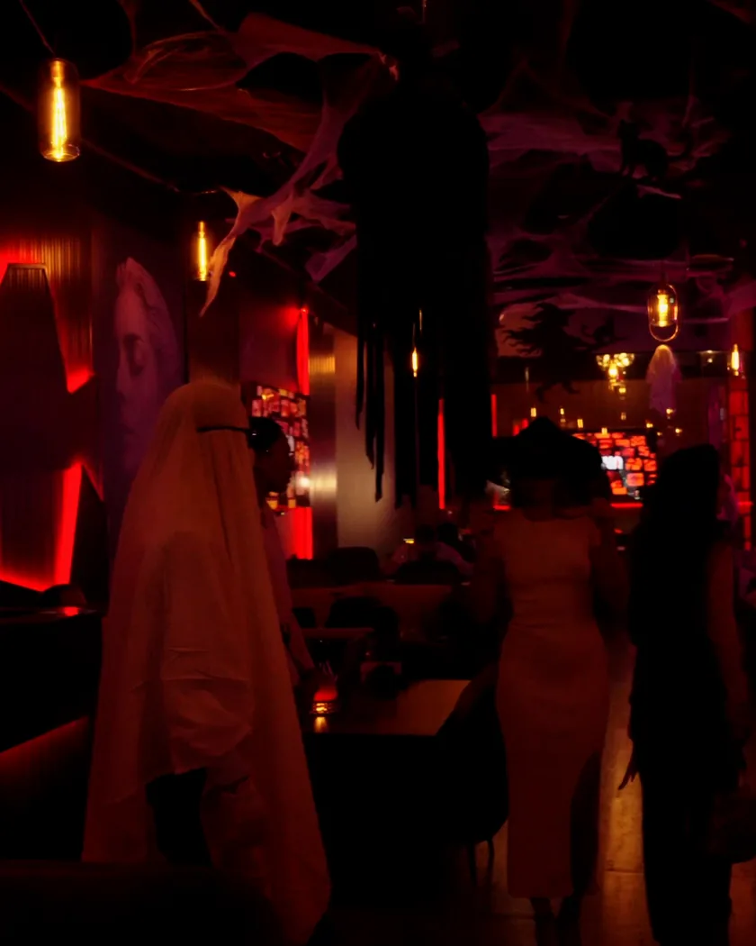 A guest in a ghost costume walking through the lounge under cobwebs