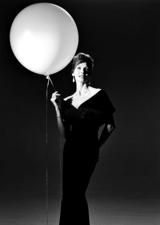 A woman in an evening dress holding a large balloon