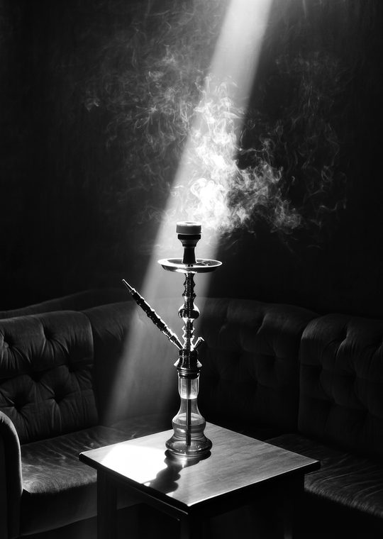 A shisha pipe with smoke curling through a beam of light