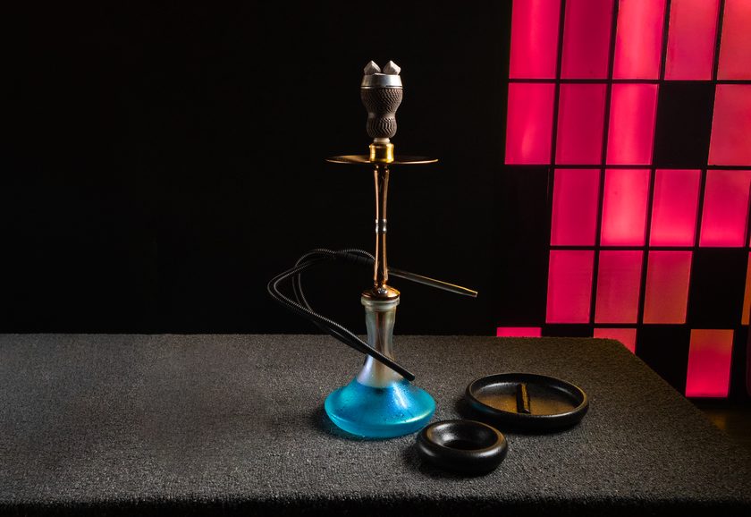 A shisha with a classic patterned clay bowl beside an ashtray
