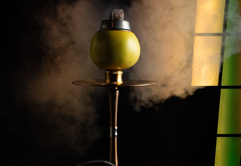 A shisha with a fresh grapefruit as the head, smoke drifting across the frame